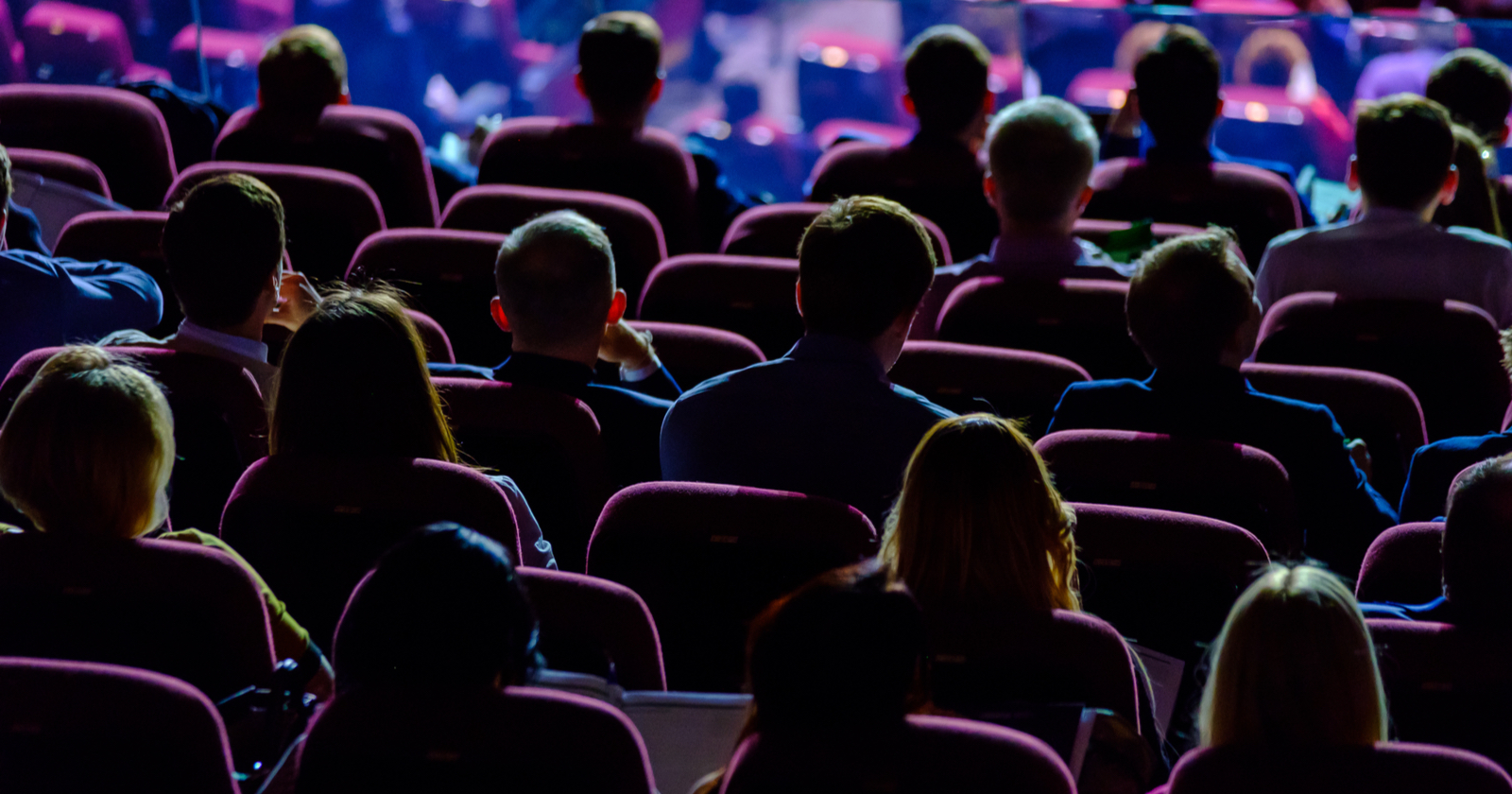 The backs of an audience watching a stage