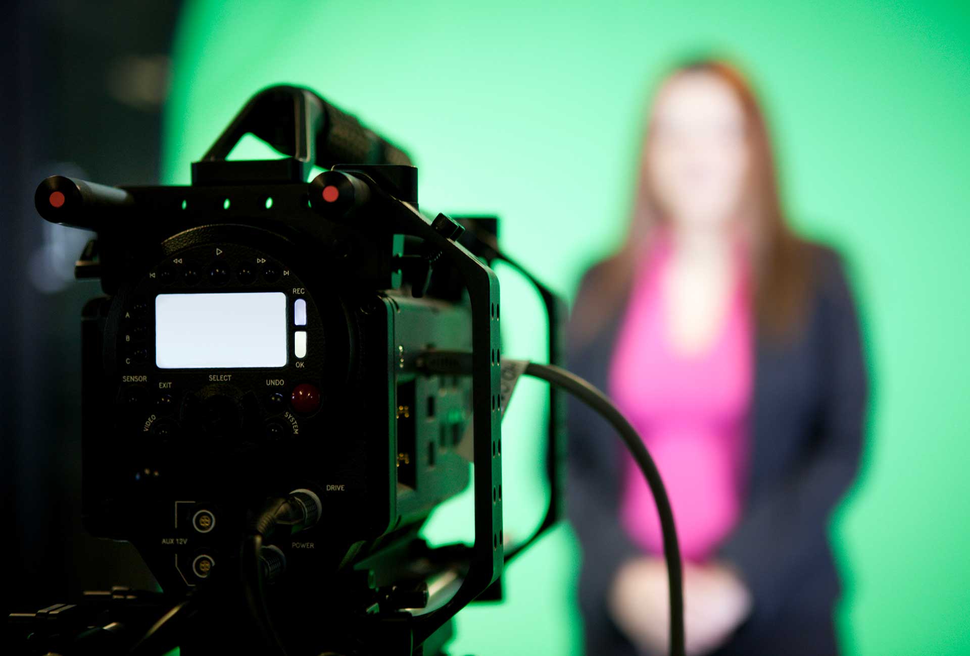 A camera recording a women in front of a green screen